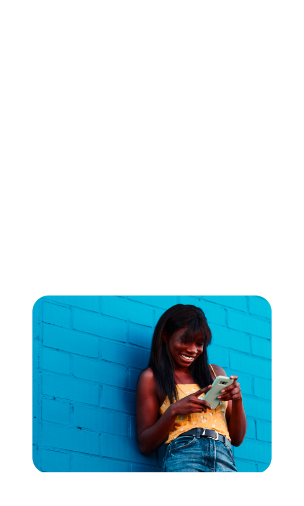 A smiling young woman casually
leans against a wall while looking at
her tax return on her smartphone